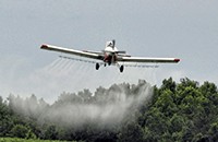small airplane in flight spraying insecticide