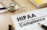 papers labeled HIPAA Compliance on desk with stethoscope