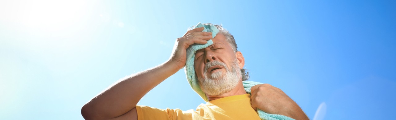 older man outside under sun, looking exhausted and hot